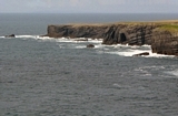 The Ross Formation on the north east side of Loop Head photographed by David Pyles over the Atlantic in a hellicopter. The rocks are represented by turbidite sheet sands that accumulated as deepwater fan lobes that were dissected by sparse shallowly incised channels. As Elliot (2000) records these are the thicker bedded, high net-to-gross, sheet turbidites of the lower part of the Ross Sandstone Formation turbidite system. The height of these cliffs is between 45-50 m. Note the shaley partings that may compartmentalize these sands and seperate them in terms of their reservoir quality from those above. Channeling may enhance vertical reservoir continuity between the stacked sheets