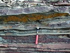 Alternating sand and shale lenticular sheets that accumulated within fining upward deepwater turbidite fans with sparse channeling expressed by cut and fill.